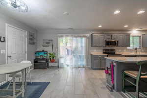 Kitchen featuring gray cabinetry, stainless steel appliances, light countertops, a sink, and recessed lighting