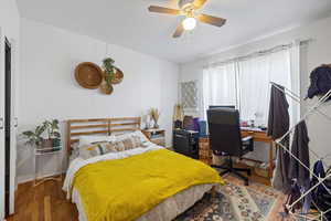 Bedroom with wood finished floors, an office area, and ceiling fan