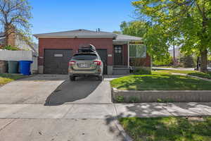 View of front facade with concrete driveway, brick siding, an attached garage, and a front lawn