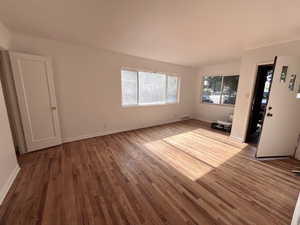 Unfurnished living room featuring wood finished floors and baseboards