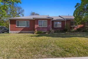 View of front of house with a front yard, brick siding, and roof with shingles