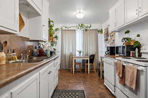 Kitchen featuring white appliances, a sink, decorative backsplash, and white cabinets