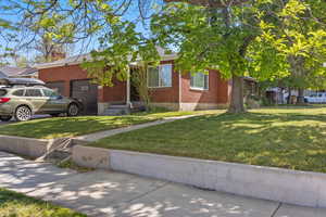 View of front of home featuring brick siding, a front yard, a chimney, and an attached garage