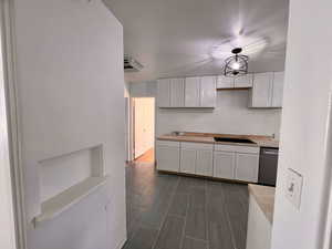 Kitchen with dishwasher, white cabinets, light countertops, and a sink