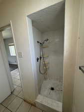 Full bath featuring a shower stall, tile patterned floors, a textured ceiling, and a textured wall