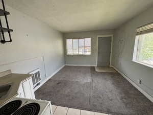 Unfurnished dining area featuring a textured ceiling, carpet floors, baseboards, and tile patterned floors