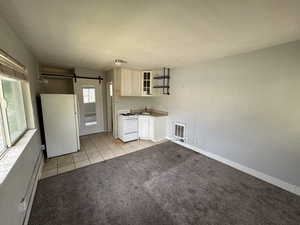Kitchen featuring white appliances, open shelves, a sink, a barn door, and light tile patterned floors