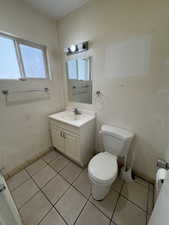 Half bathroom featuring toilet, vanity, and tile patterned floors