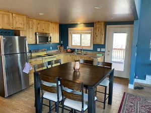 Kitchen featuring appliances with stainless steel finishes, light brown cabinetry, light wood finished floors, recessed lighting, and a sink