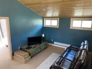 Carpeted living area with wood ceiling, a baseboard heating unit, vaulted ceiling, and baseboards