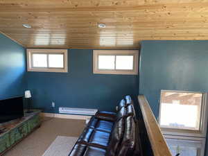 Interior space featuring a baseboard radiator, wooden ceiling, and baseboards