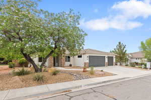 View of front of home featuring driveway, a garage, stucco siding, and stone siding