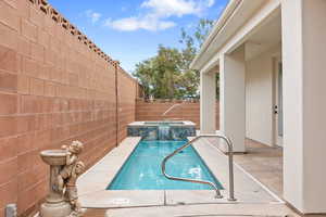 View of swimming pool with a fenced backyard, a pool with connected hot tub, and a patio