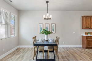 Dining space with light wood finished floors, plenty of natural light, a chandelier, and baseboards