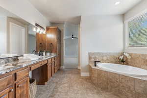 Bathroom with double vanity, a bath, ceiling fan, and baseboards