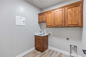Laundry area featuring cabinet space, light wood finished floors, washer hookup, hookup for an electric dryer, and baseboards