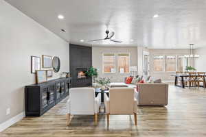 Living room featuring healthy amount of natural light, a fireplace, a ceiling fan, baseboards, and a textured ceiling