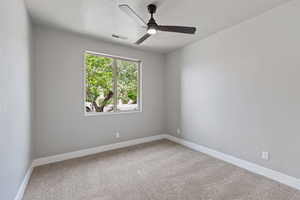 Carpeted empty room with a ceiling fan and baseboards