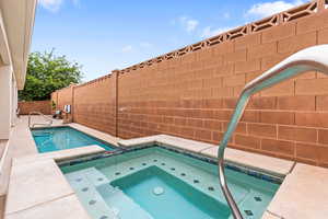 View of pool featuring an in-ground hot tub and a fenced backyard