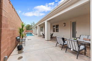View of patio featuring outdoor dining space, a fenced backyard, and a pool with connected hot tub