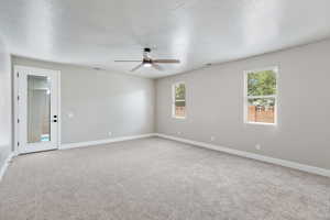 Carpeted empty room featuring a ceiling fan, baseboards, and healthy amount of natural light