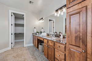 Bathroom featuring vanity, a walk in closet, and baseboards