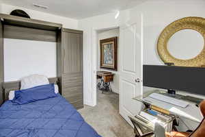 Bedroom featuring light carpet, baseboards, and a desk