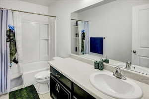 Full bathroom with toilet, tile patterned floors, vanity, and shower / bath combo with shower curtain
