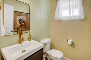 Half bath with toilet, vanity, and baseboards