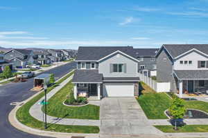 Traditional-style home featuring a residential view, concrete driveway, an attached garage, and a shingled roof