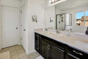 Full bath with tile patterned floors, a stall shower, vanity, and baseboards