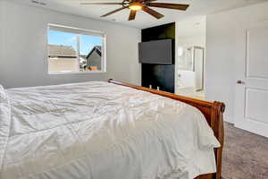 Carpeted bedroom featuring a ceiling fan and ensuite bath