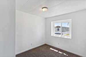 Carpeted empty room with baseboards and a textured ceiling