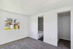 Unfurnished bedroom featuring carpet flooring, baseboards, a walk in closet, and a closet