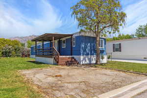 Manufactured / mobile home featuring a porch, a front lawn, and a mountain view