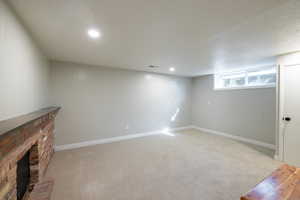 Basement featuring light colored carpet, a fireplace, and baseboards