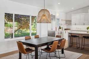 Dining room with light wood-type flooring, lofted ceiling, baseboards, and recessed lighting