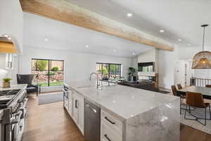 Kitchen featuring a sink, appliances with stainless steel finishes, open floor plan, white cabinets, and plenty of natural light