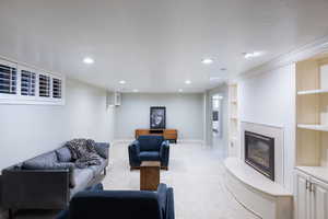 Living room featuring light colored carpet, recessed lighting, and a fireplace