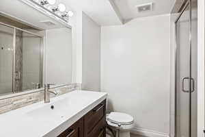 Bathroom featuring a shower stall, toilet, tasteful backsplash, and vanity