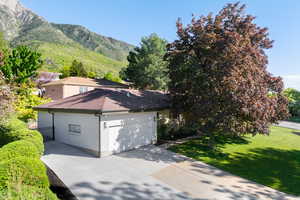 View of side of home featuring a garage, concrete driveway, brick siding, a yard, and a mountain view