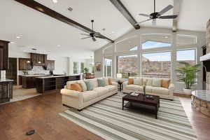 Living room featuring beamed ceiling, a fireplace with raised hearth, light wood finished floors, high vaulted ceiling, and recessed lighting