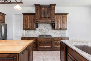 Kitchen with dark brown cabinetry, backsplash, and butcher block countertops