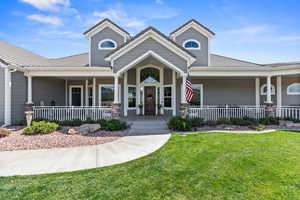 View of front facade featuring covered porch, a front yard, and a tiled roof