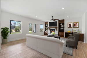Living area featuring a glass covered fireplace, recessed lighting, light wood-style floors, and ceiling fan