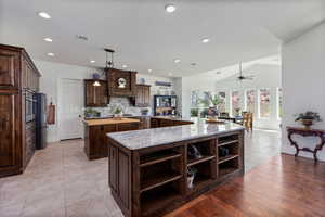 Kitchen featuring open shelves, a spacious island, dark brown cabinets, tasteful backsplash, and a ceiling fan