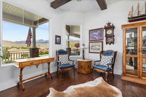 Living area with beam ceiling, a mountain view, hardwood / wood-style floors, baseboards, and decorative columns