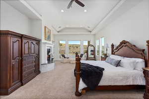 Carpeted bedroom with lofted ceiling, recessed lighting, access to exterior, a warm lit fireplace, and ceiling fan