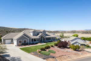 View of front of home with an attached garage, driveway, a front lawn, and a mountain view