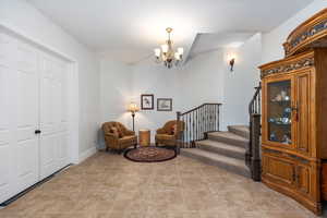 Living area with a chandelier, light tile patterned flooring, and stairway